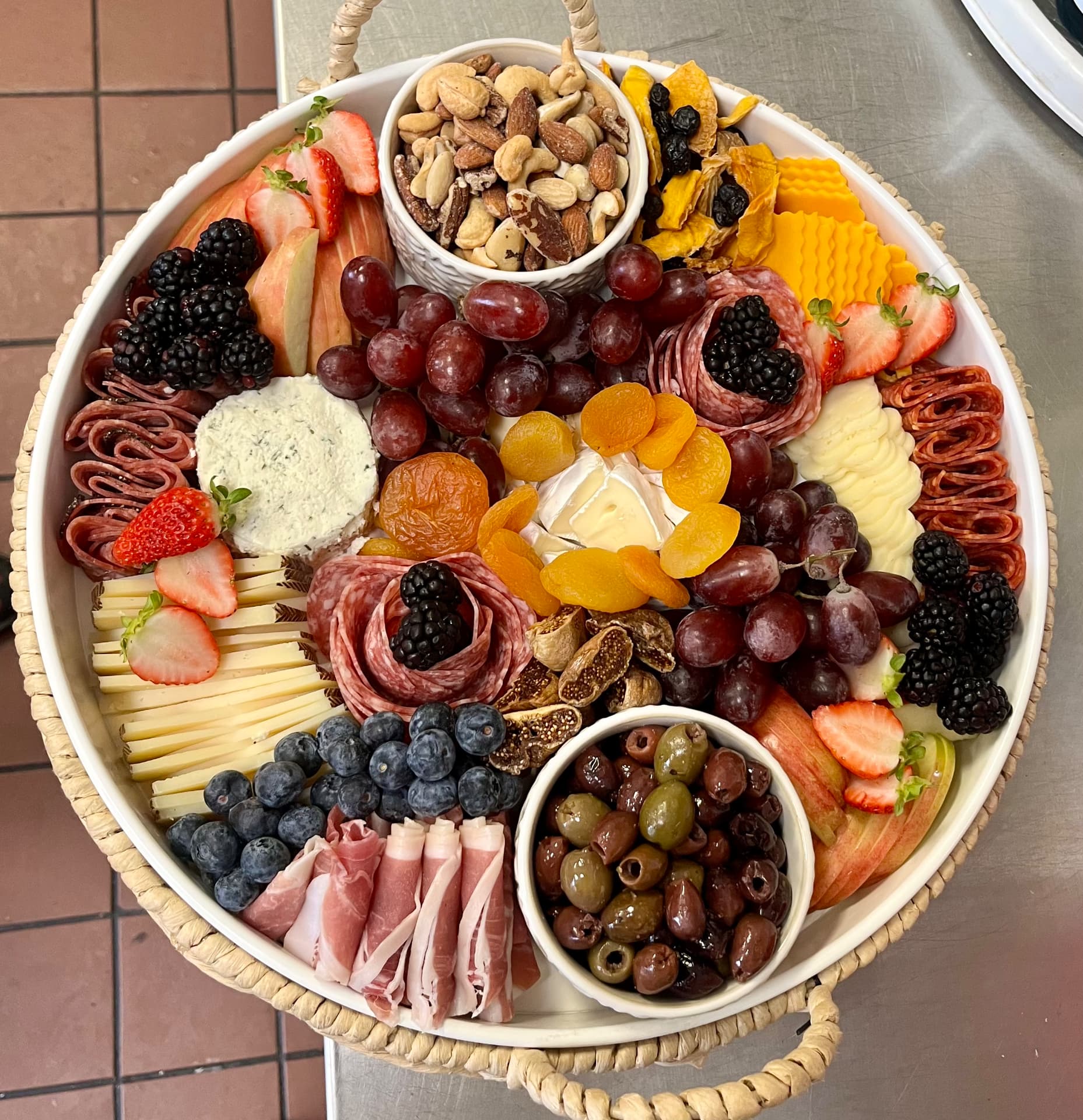 Round charcuterie platter with salami roses, berries, cheeses and olives