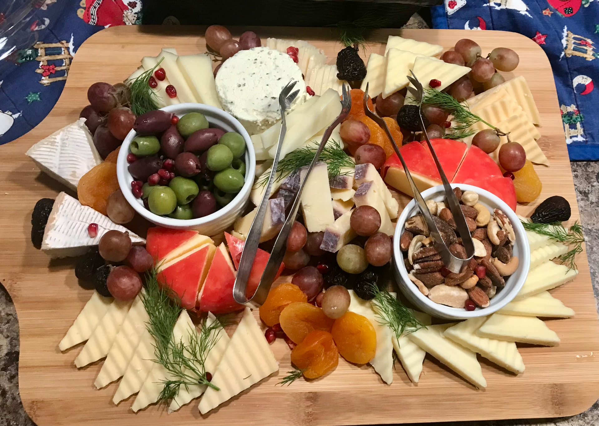 Cheese board with olives, nuts, apricots and grapes